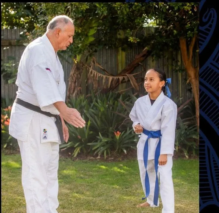 Renshi Manuera Riwai teaching a tamaiti on the grass outside the kura